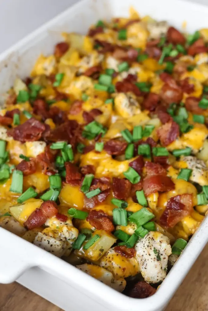 Sliced Chicken Potato Casserole in a casserole dish, showing layers of crispy potatoes, tender chicken, smoky bacon, and melted cheddar cheese.