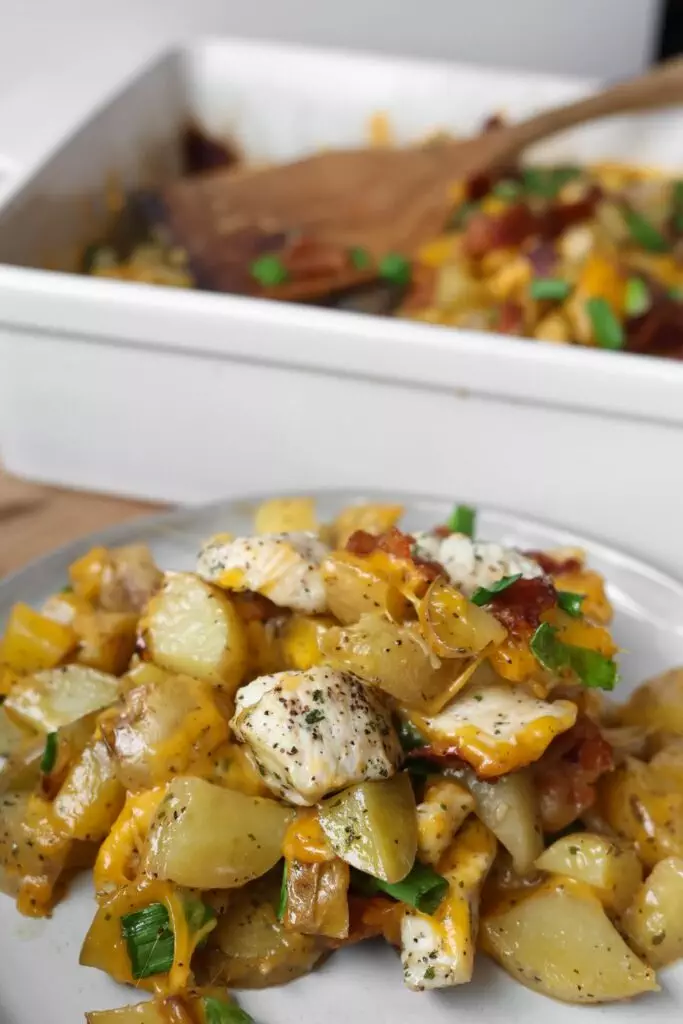 A close-up shot of Chicken Potato Casserole on a plate, showing layers of tender chicken, crispy bacon, and golden potatoes, all topped with melted cheese.