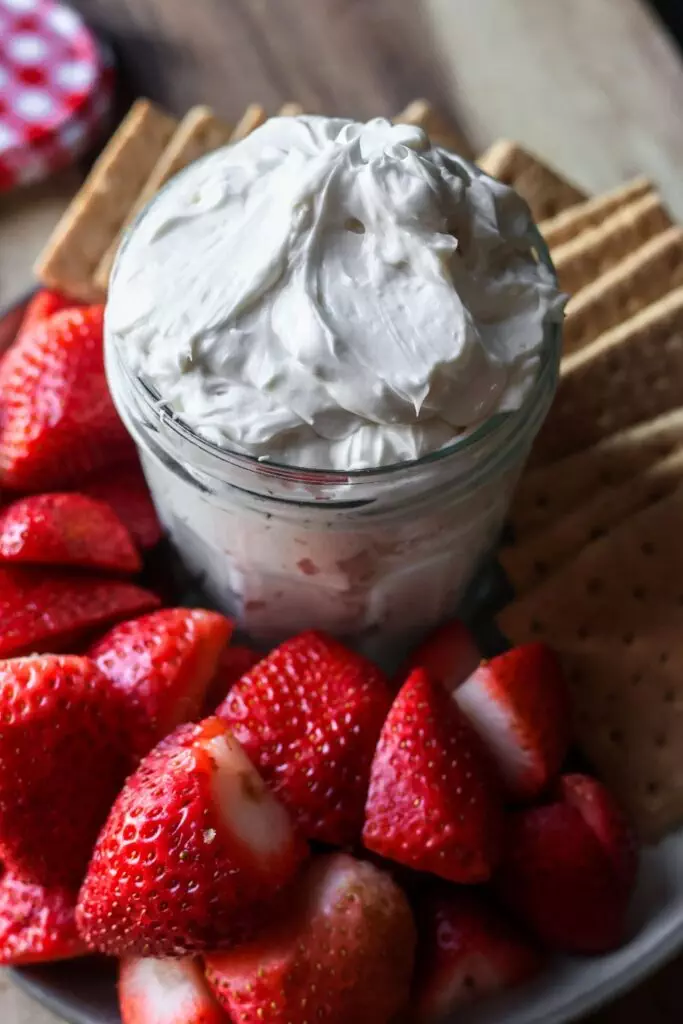 Jar of homemade cheesecake dip with strawberries and graham crackers